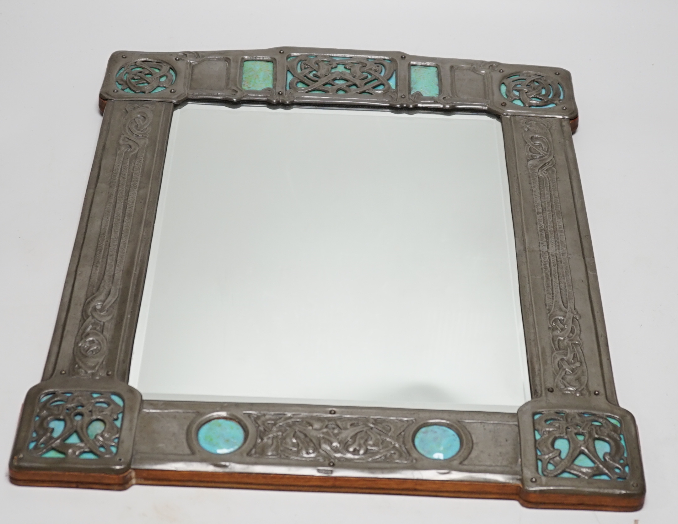 A Miller Brothers Art Nouveau embossed pewter mirror with cabochon turquoise enamel bosses, 48cm high x 39cm wide